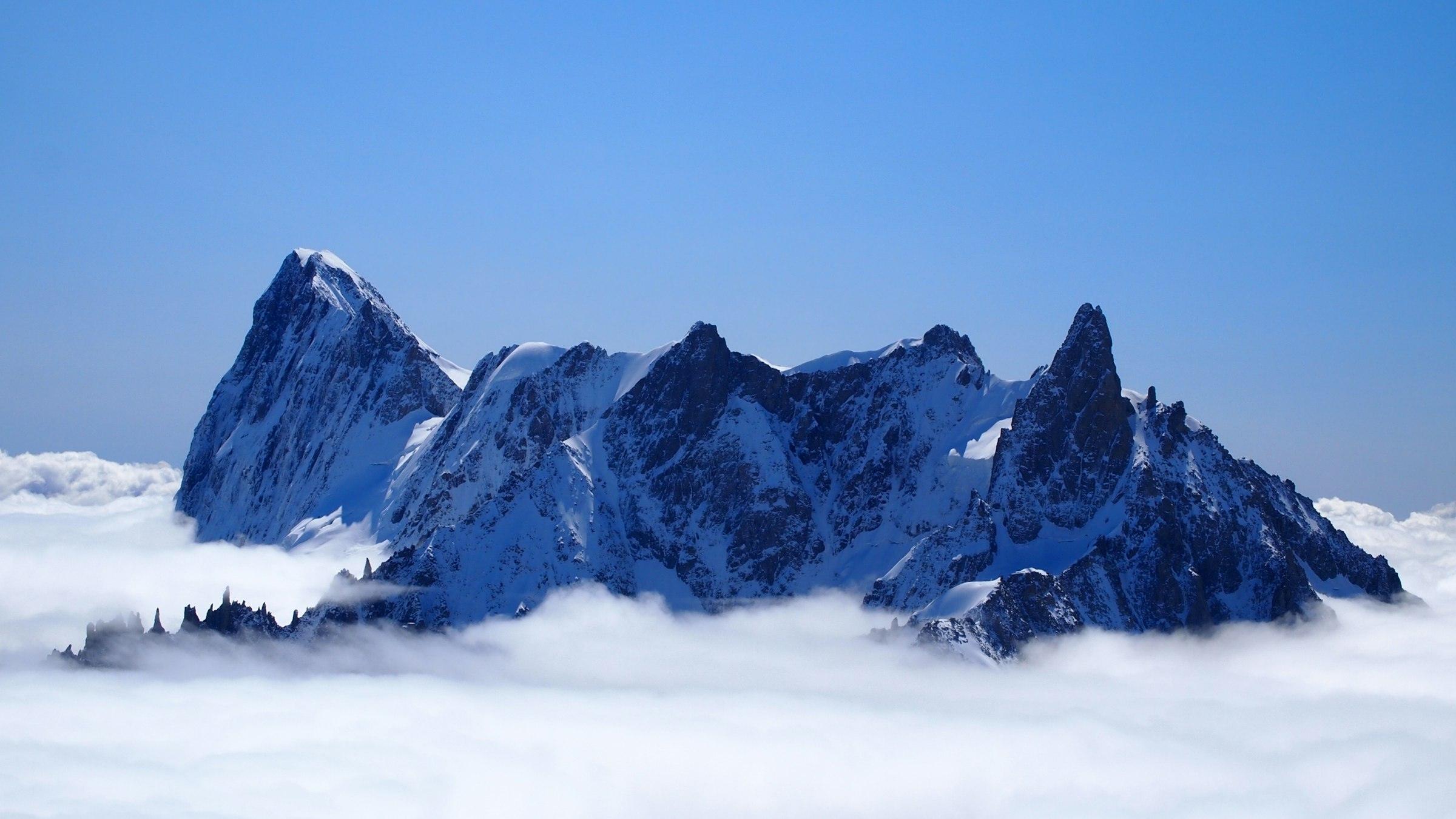 Bergtoppen van het Mont Blanc-massief boven een wolkendek, strakblauwe lucht