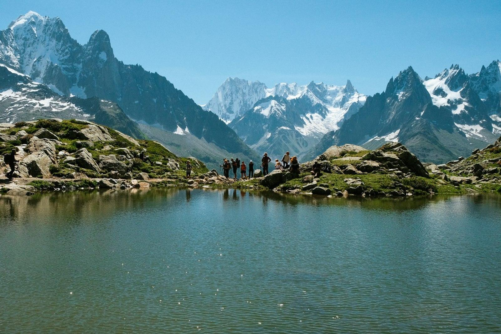 Een groep wandelaars bij een bergmeer, met rotspieken erachter
