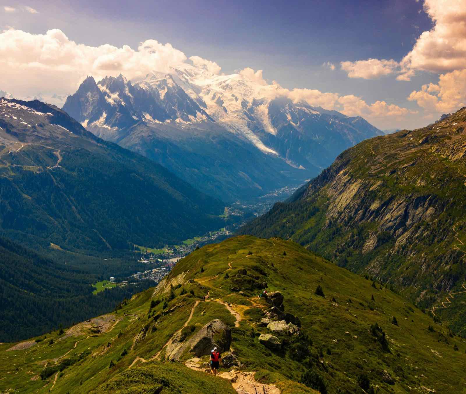 Zomer in de vallei van Chamonix: groene graat met een wandelpad, de Mont Blanc met sneeuw op de top en blauwe lucht
